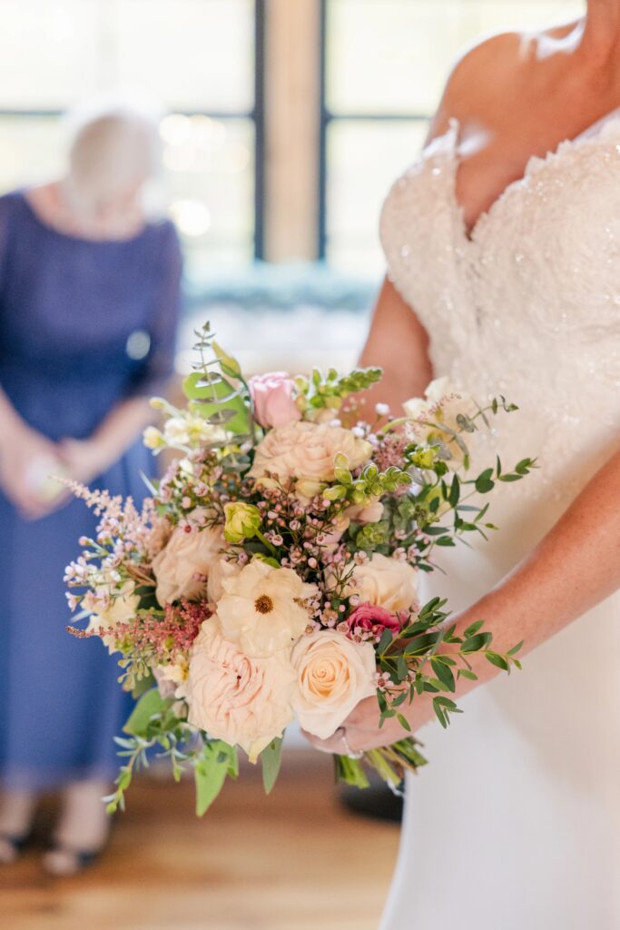 A closeup of a pink and cream bridal bouquet, held by the bride. Designed by One Last Avocado Floral Design.