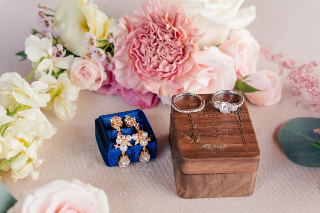 Ring detail photo with a wooden box and flowers.
