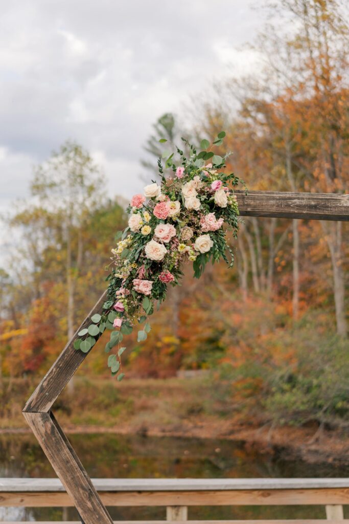 A closeup of wedding florals on a wooden hexagon arbor. The flowers are pink and cream. Designed by One Last Avocado Floral Design at Silver Fox Lavender Farm.