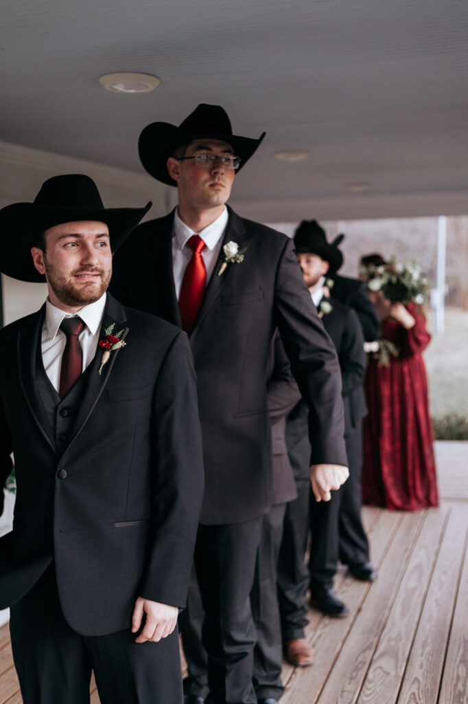 A groom stands in front of his groomsmen, they wear black cowboy hats. Wedding venue: 48 Fields Farm. Florist: One Last Avocado Floral Design