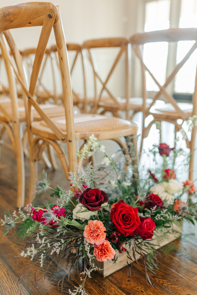 Romantic indoor wedding ceremony aisle with garden-style florals and glowing candlelight
