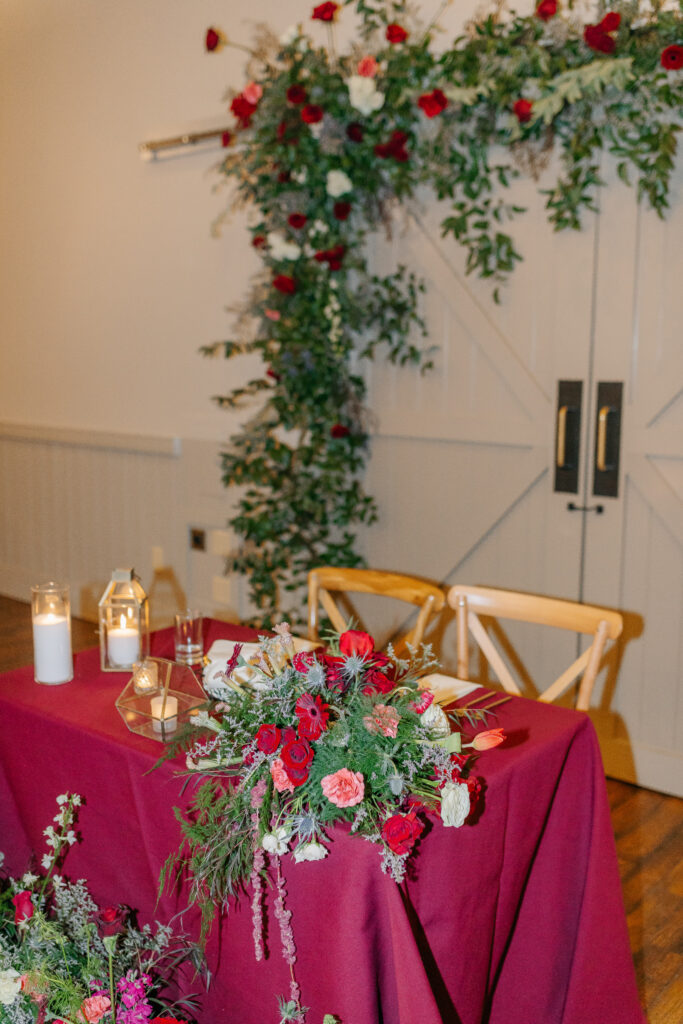 Romantic sweetheart table floral installation with colorful red garden-style winter flowers at King Family Vineyards