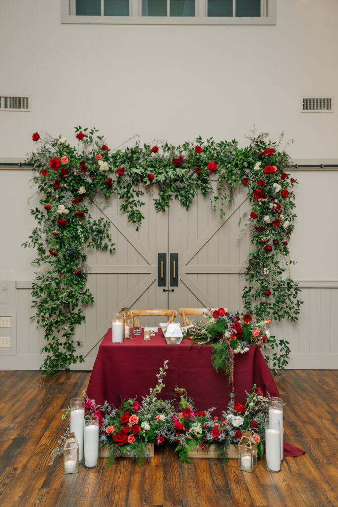 Romantic sweetheart table floral installation with colorful red garden-style winter flowers at King Family Vineyards