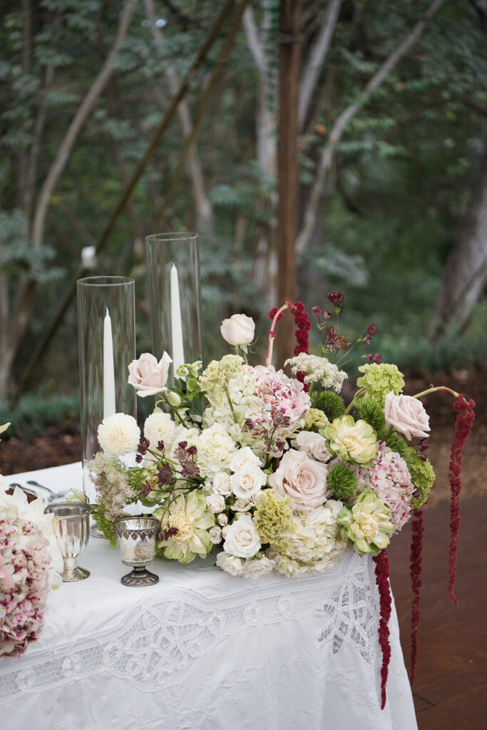 Modern wedding reception centerpieces with hydrangeas, dahlias, and calla lilies in blush, burgundy, and chartreuse tones